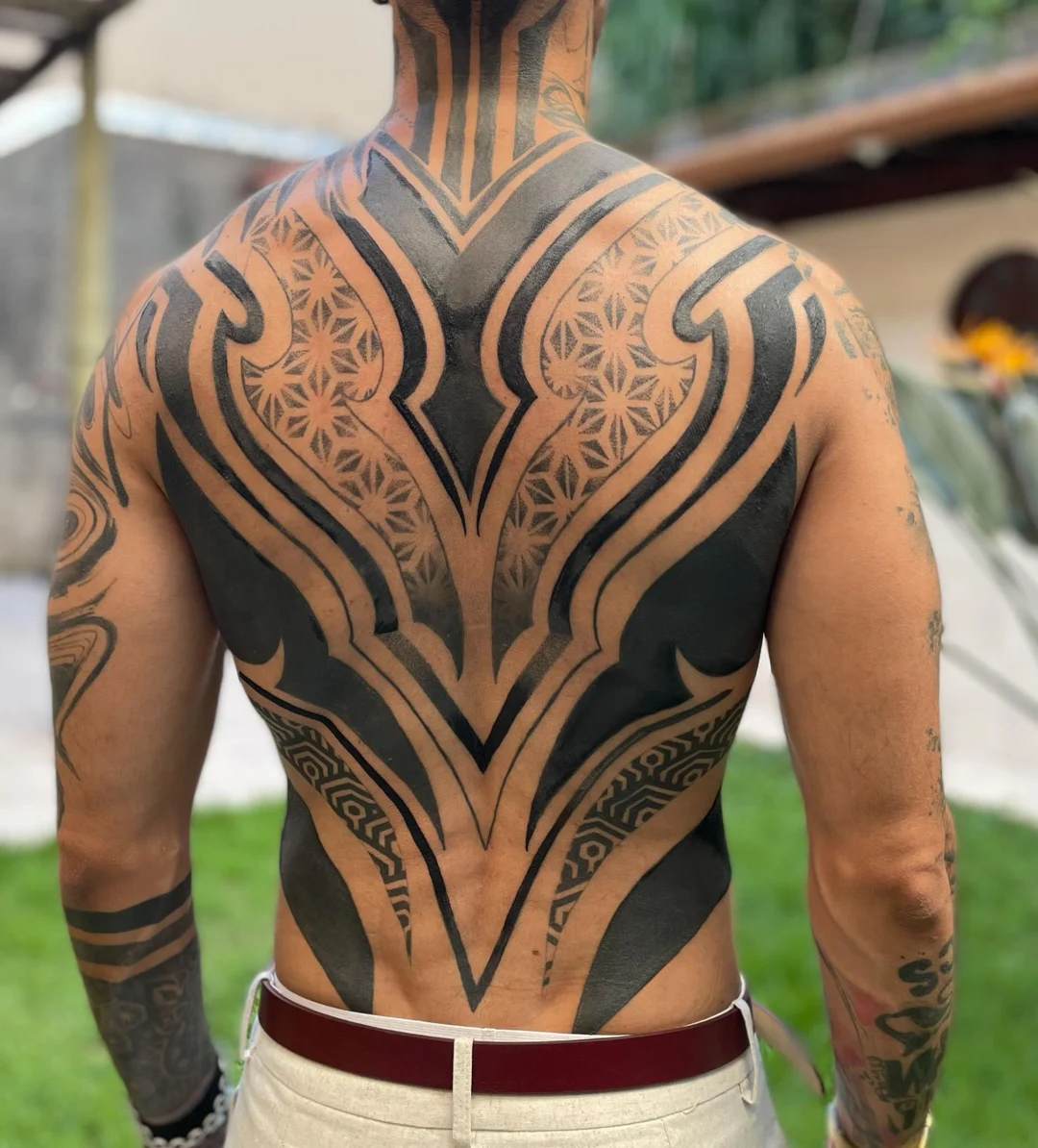 Costas com tatuagem preta ornamental desenvolvida por Anny e Kamila Medeiros