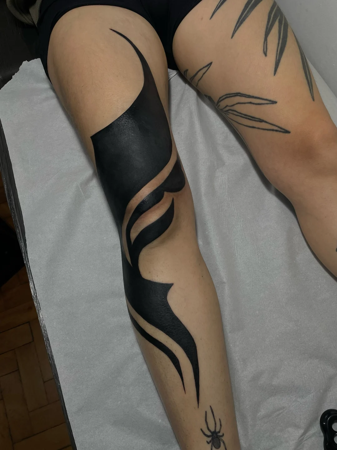 Tatuagens pretas com linhas curvas nas pernas, em projeto de coverup